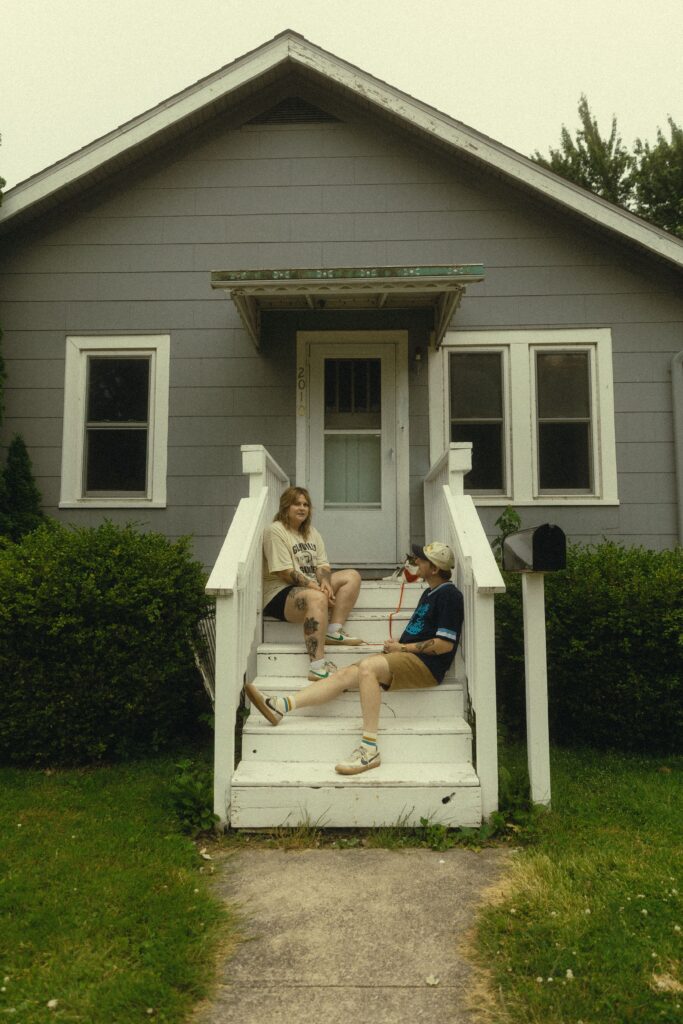 during their couples photography, a couple sit on different stairs in front of their home