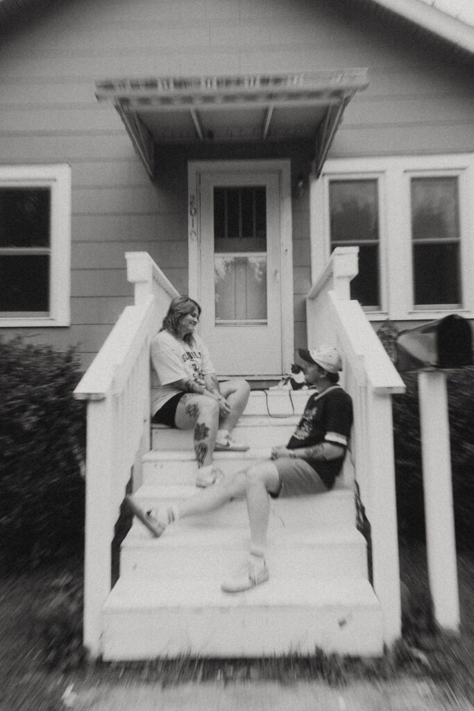 during their couples photography, a michigan couple smile at each other from the steps of their home