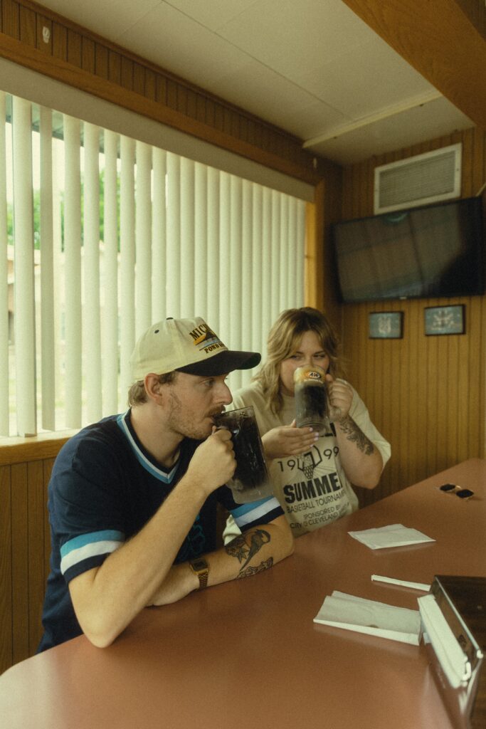 during their couples photography, a couple sits together at the a&w bar and drink root beer