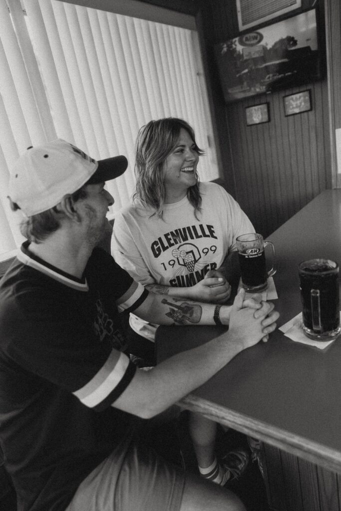 a couple smiles together as they sit at the bar at a&w