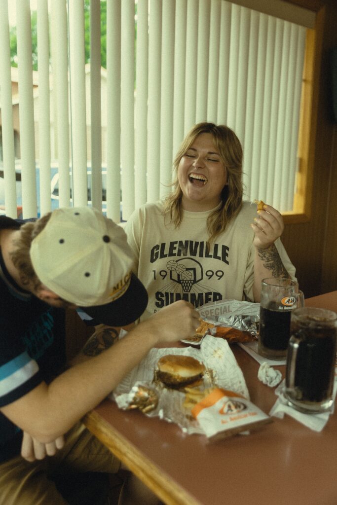 a couple laugh together during their engagment photos at a&w