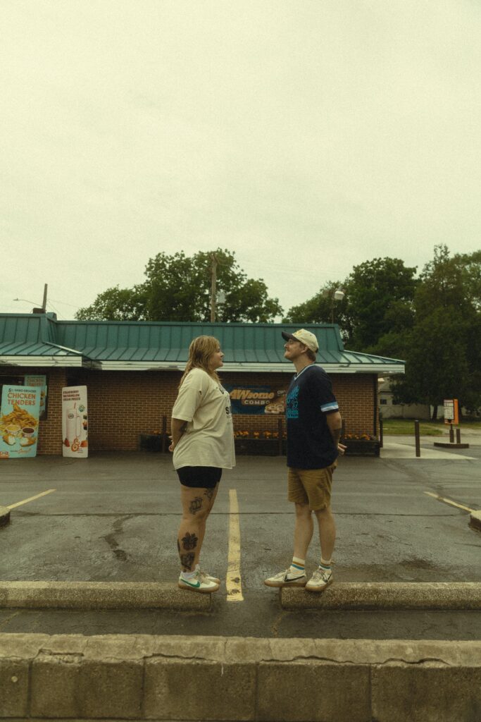 a couple stand on separate parking barriers facing each other