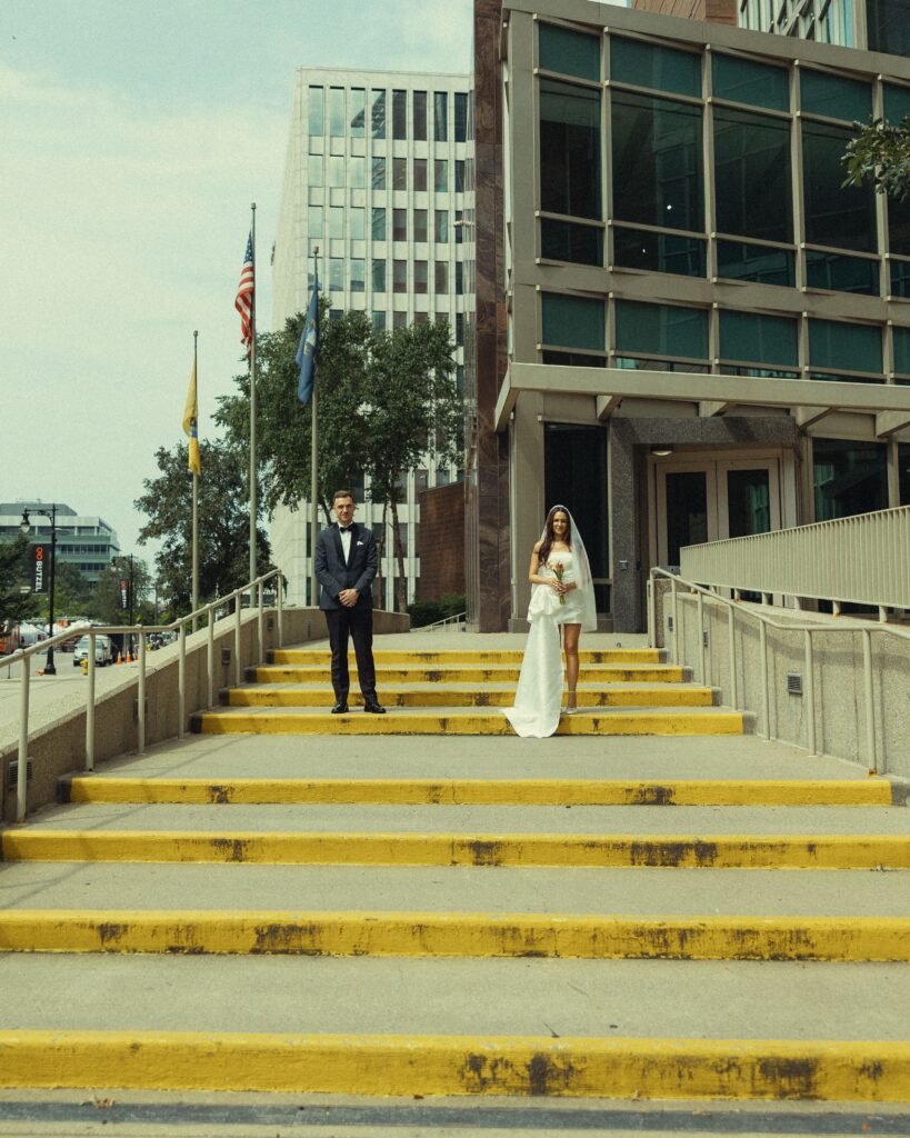 a couple in wedding outfits stand in front of an mi courthouse while eloping in michigan