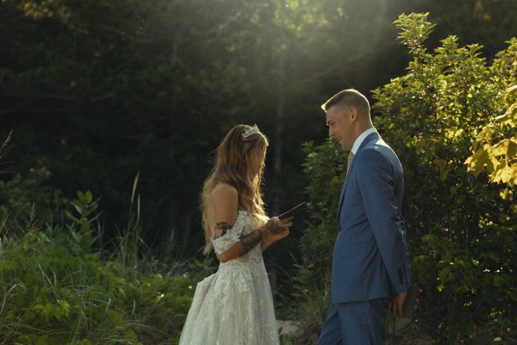 how to elope in michigan, a couple share their vows in enchanting greenery with the sun peeking through