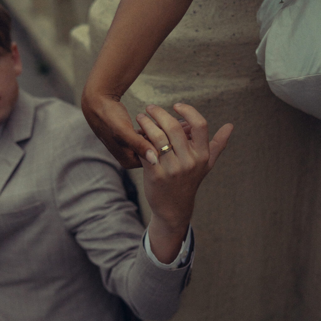 a cropped photo of a couple holding hands to show his wedding ring