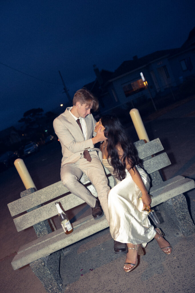 a couple look at each other as they sit on a bench