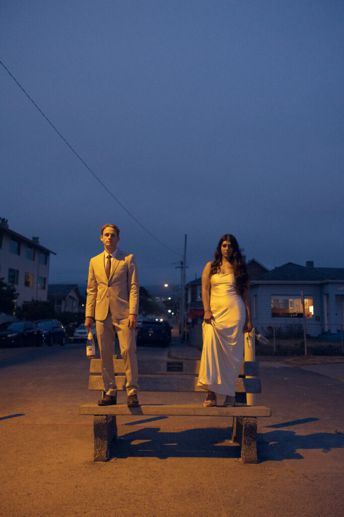 elopement photography, a couple stands on a bench in the light from a lamppost