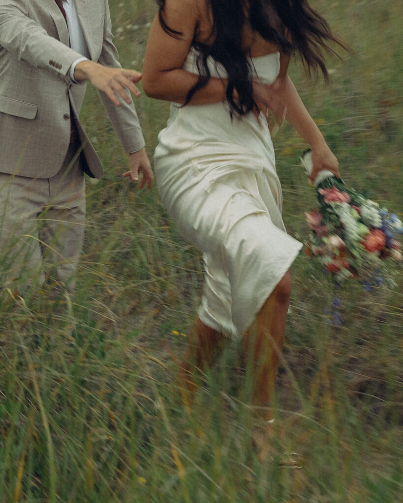 elopement photography of a couple walking through a field in wedding attire