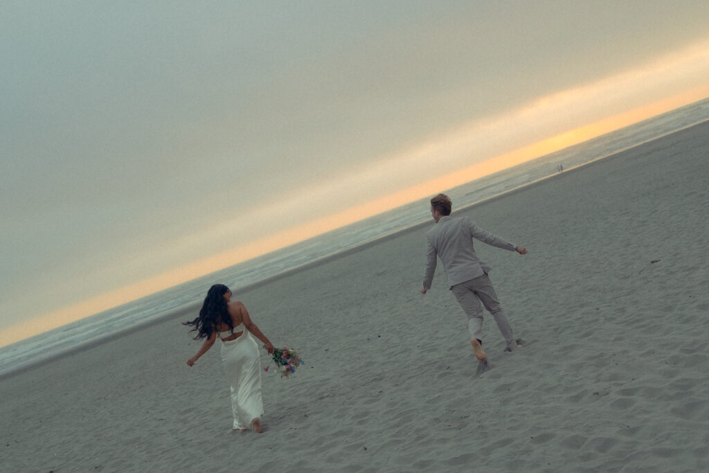 a couple in wedding attire runs around the beach during elopement photography for their wedding