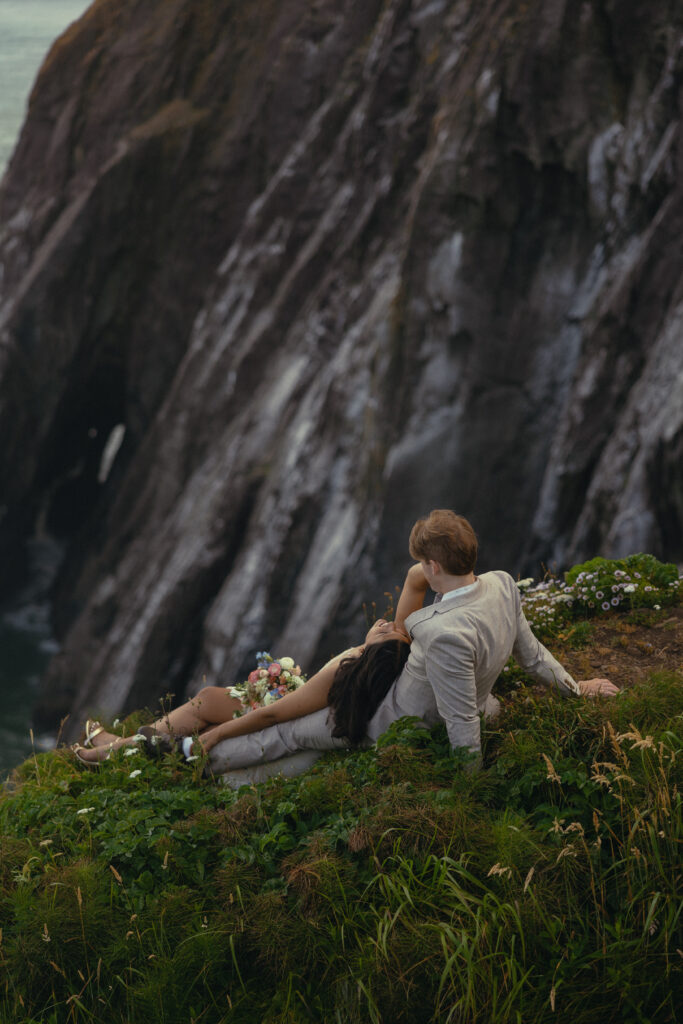 a couple sit on a grassy patch of an oregon mountain during their elopement