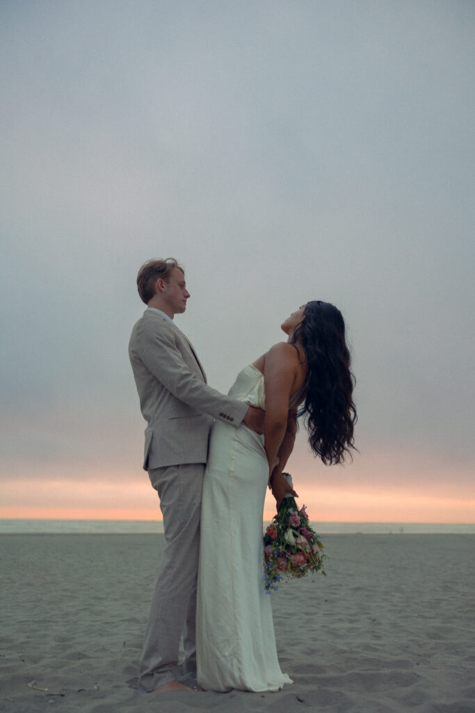 a couple on a beach at sunrise share an embrace during their oregon elopement