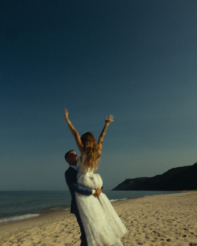 A MI beach is pictured with a newlywed couple as part of a guide to eloping in Michigan