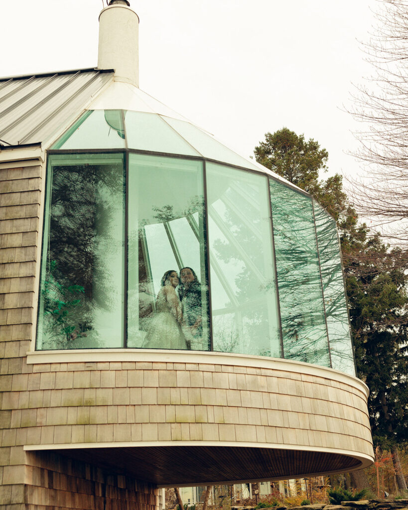 A newlywed couple is photographed through a panoramic window after eloping in Michigan