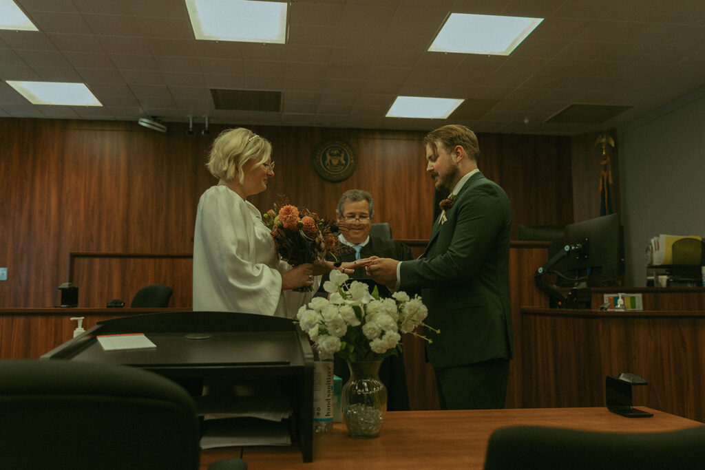 A couple exchange rings at their  courthouse ceremony while eloping in MI  