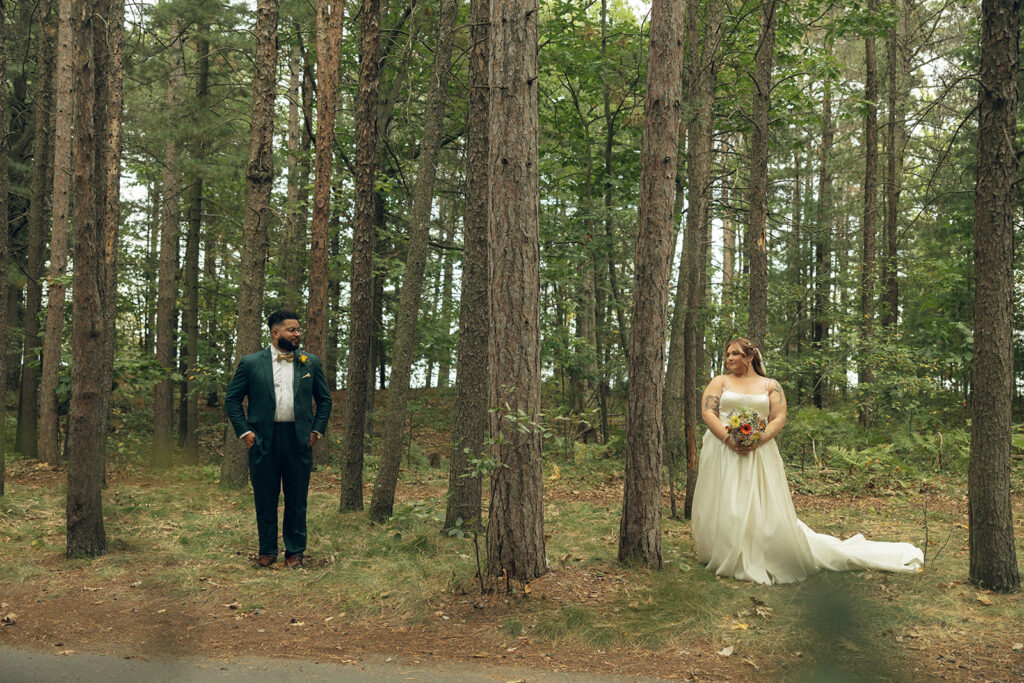 A newlywed couple is shown in a wooded area in their wedding attire, showcasing places to elope in michigan