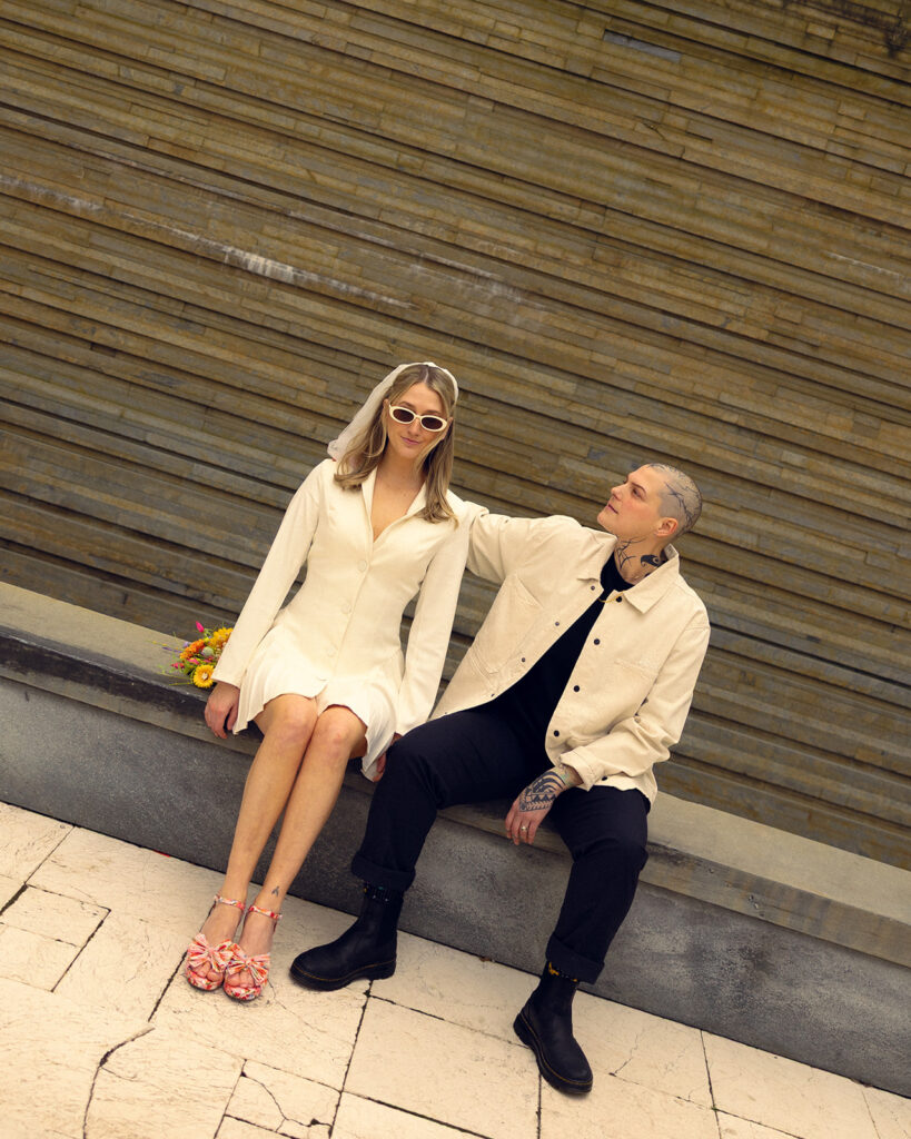 Newlyweds are photographed seated on a bench outside of GRAM, one of many places to elope in michigan