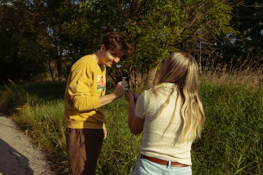 during engagement photos, a man sniffs a flower his fiancee picked for him