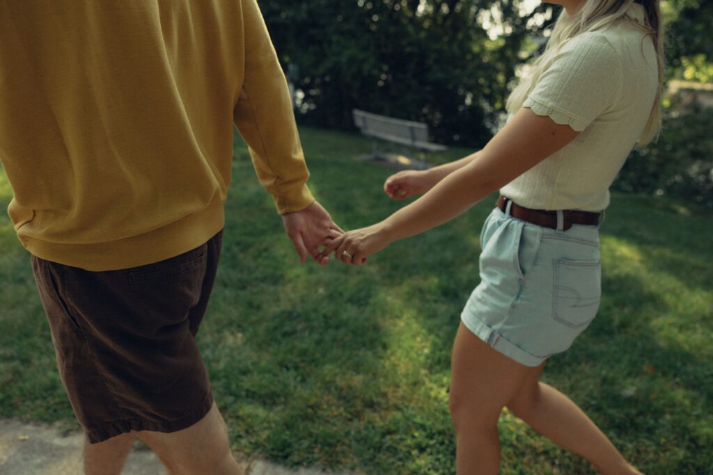 an engaged couple walk together with loosely held hands during their engagement photos grand rapids