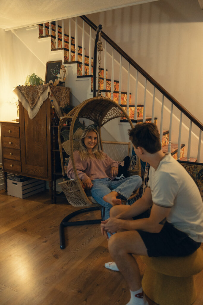 a woman sits in an egg chair and smiles at her fiance