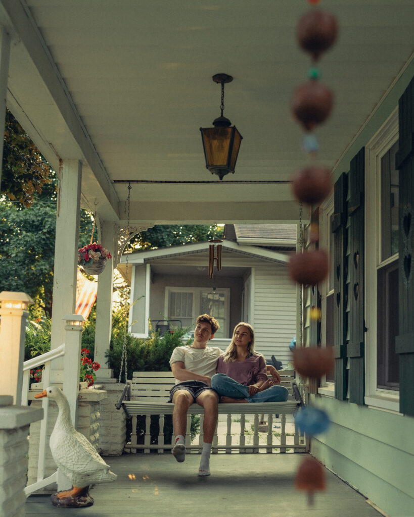 a couple sits together on a porch swing during engagement photos grand rapids