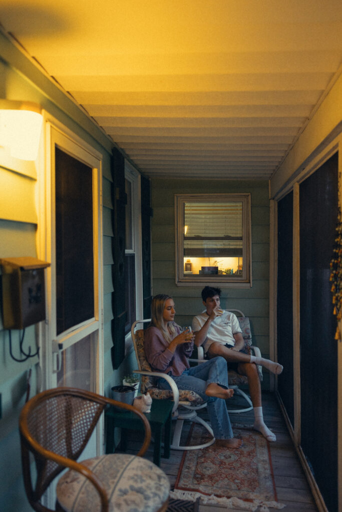 an engaged couple sit together on the porch during engagement photos grand rapids at home