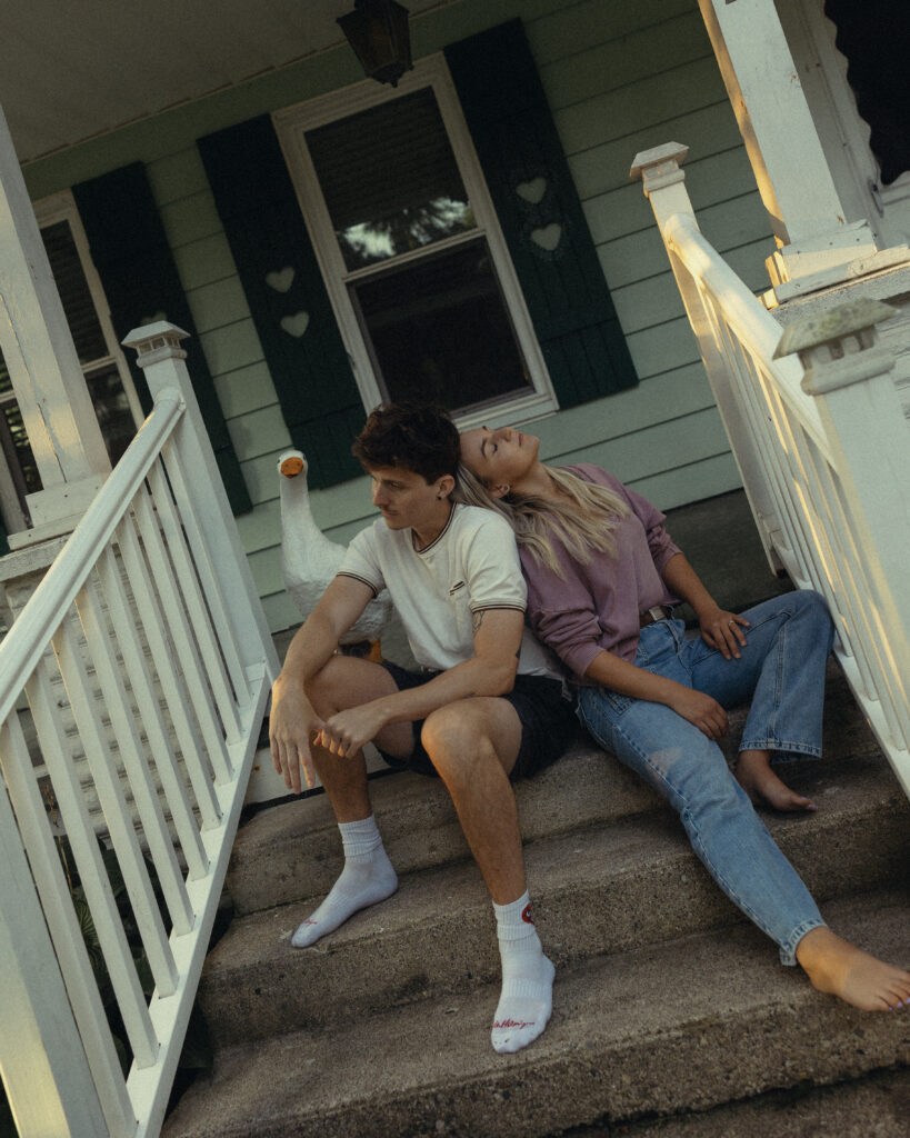 an engaged couple lean together while sitting on the front step of their home during engagement photos grand rapids