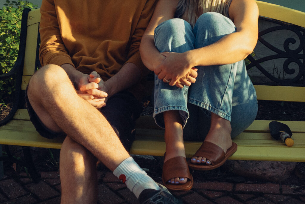 a cropped photo of an engaged couple sitting cozily together on a bench during their engagement photos grand rapids