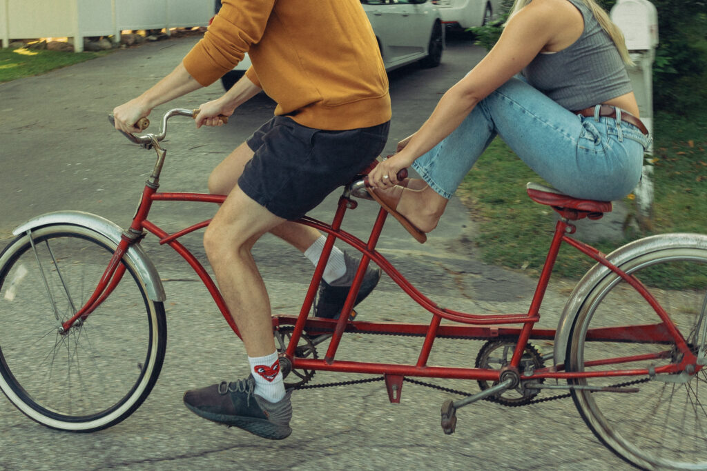 an engaged couple ride a tandem bike during their engagement photos grand rapids