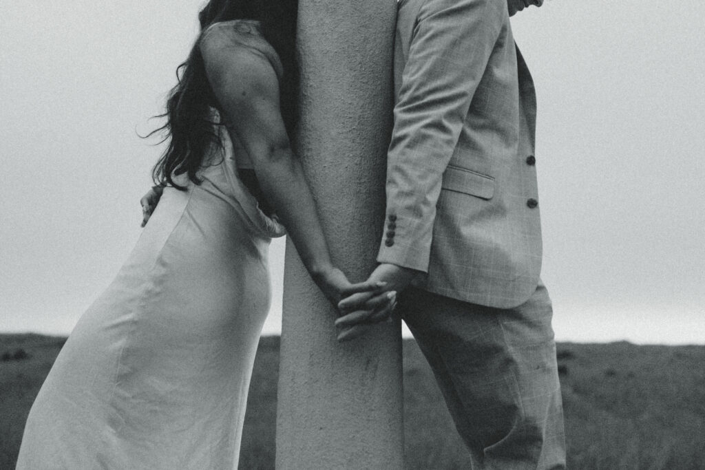 oregone elopement photography a couple stand on opposite sides of a pole and hold hands