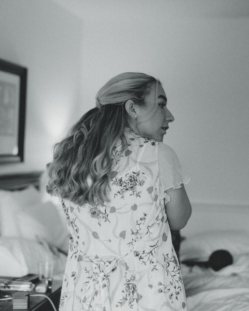 a bride puts in her earring in the hotel room during her documentary style wedding photos