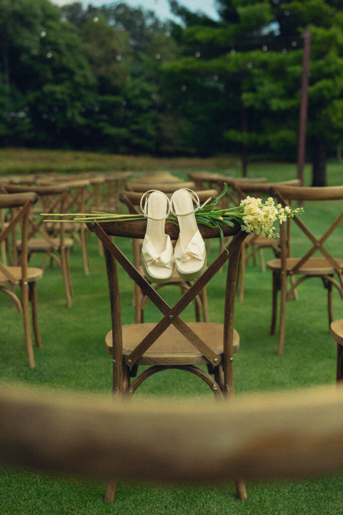 the bride's heels rest on a chair on the site of their wedding ceremony