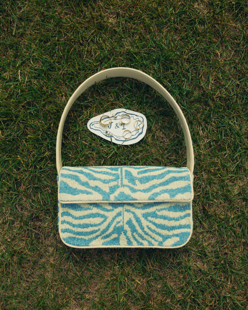 a blue zebra print purse sits in the grass with a couple's set of wedding rings