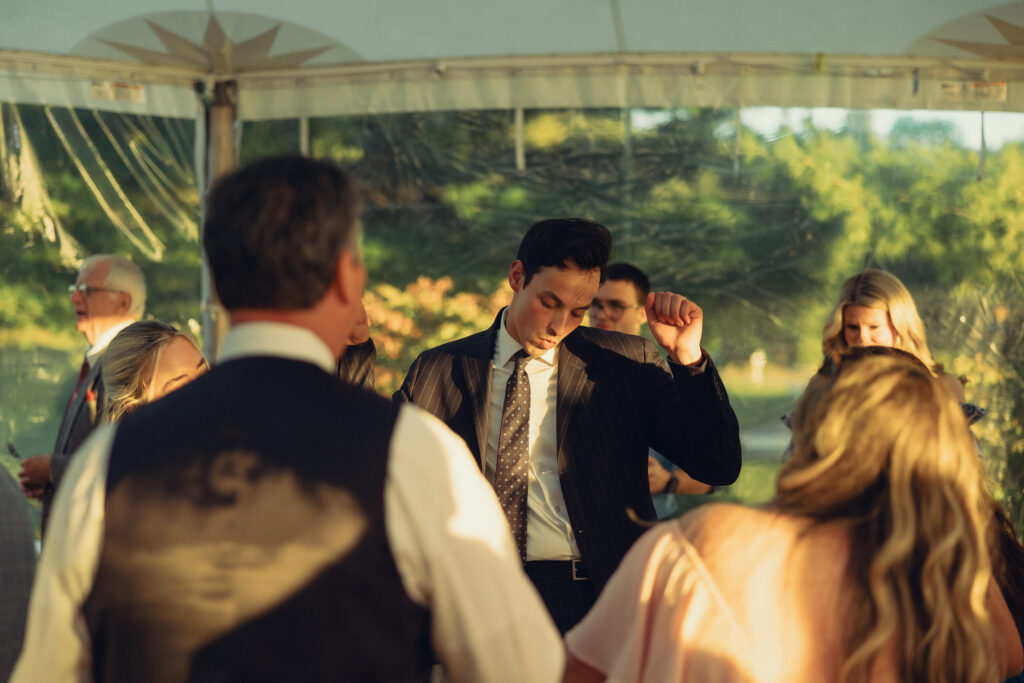 the groom does a lil dance on the dance floor surrounded by guests at their reception with documentary style wedding photos