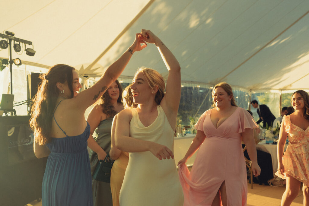 the bride spins on the the dancefloor with her bridesmaids during her reception with documentary style wedding photos