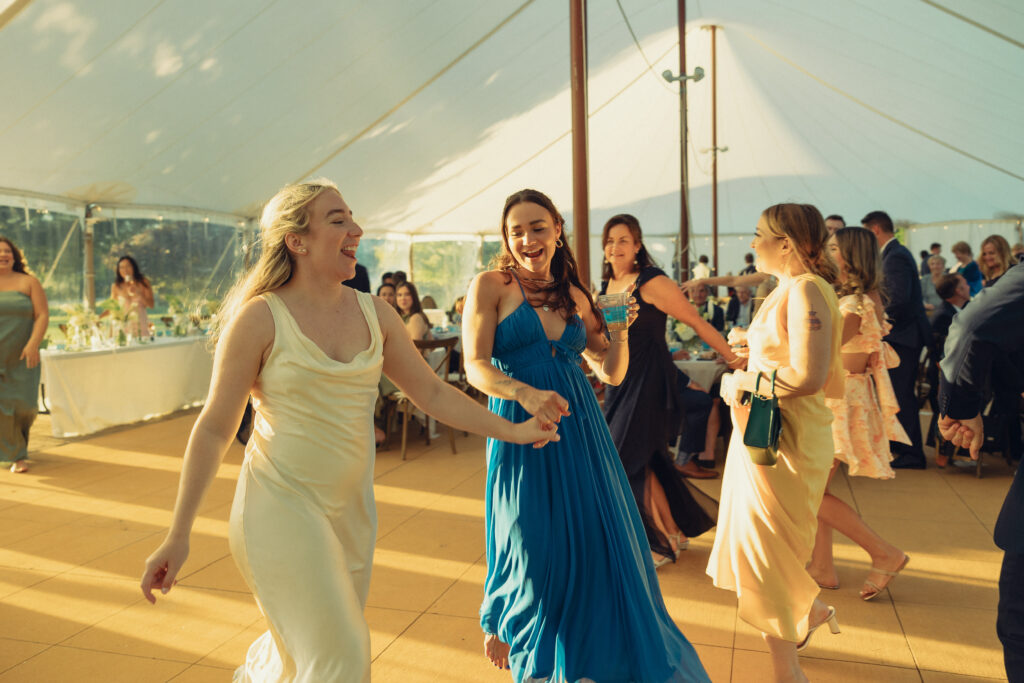 documentary style wedding photos, a bride smiles wide as she walks onto the dance floor with her guests