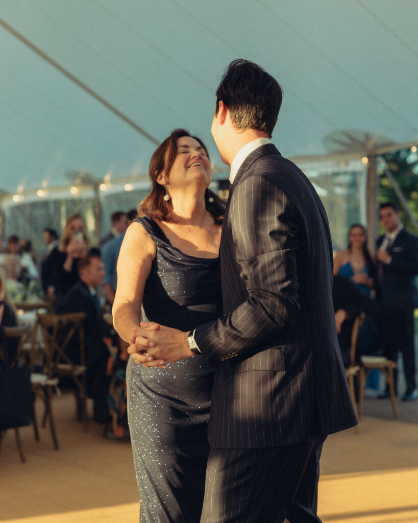 the groom and his mother smile at each other as they dance at his wedding reception with documentary style wedding photos