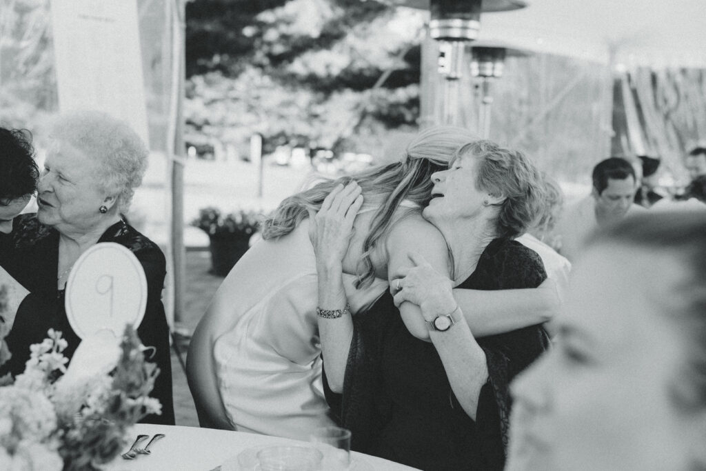 the bride shares an embrace with a wedding guest during her reception with documentary style wedding photos