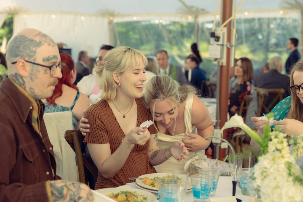 the bride laughs with a wedding guest in documentary style wedding photos