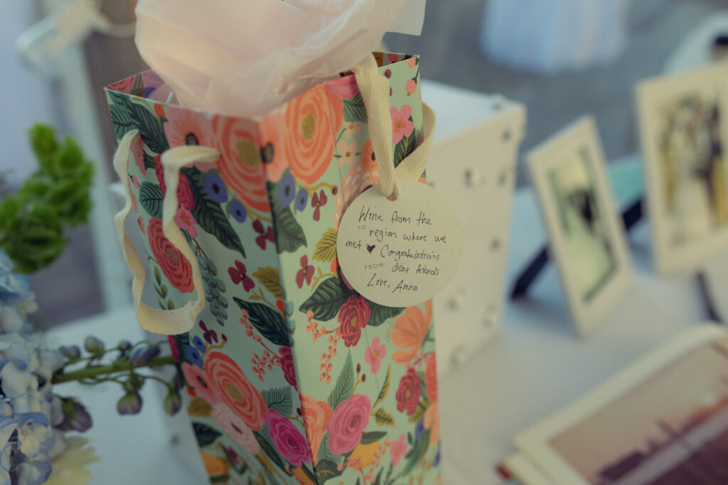 a wine gift bag with a handwritten note from the gift table at a reception with documentary style wedding photos