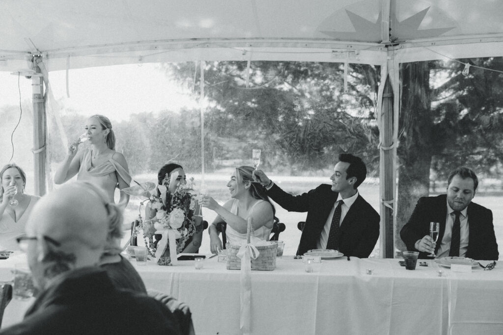 newlyweds and their guests share a cheers while smiling in documentary style wedding photos