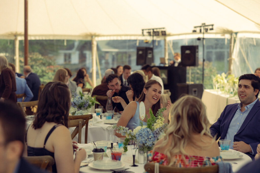 wedding guests laugh during a reception with documentary style wedding photos