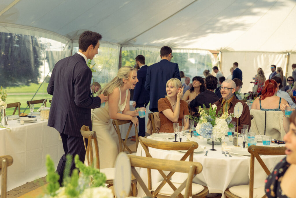 the bride and groom greet guests at table four in documentary style wedding photos