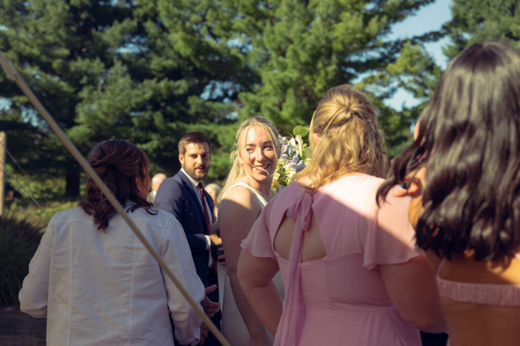 the bride looks over her shoulder surrounded by guests in this documentary style wedding photo