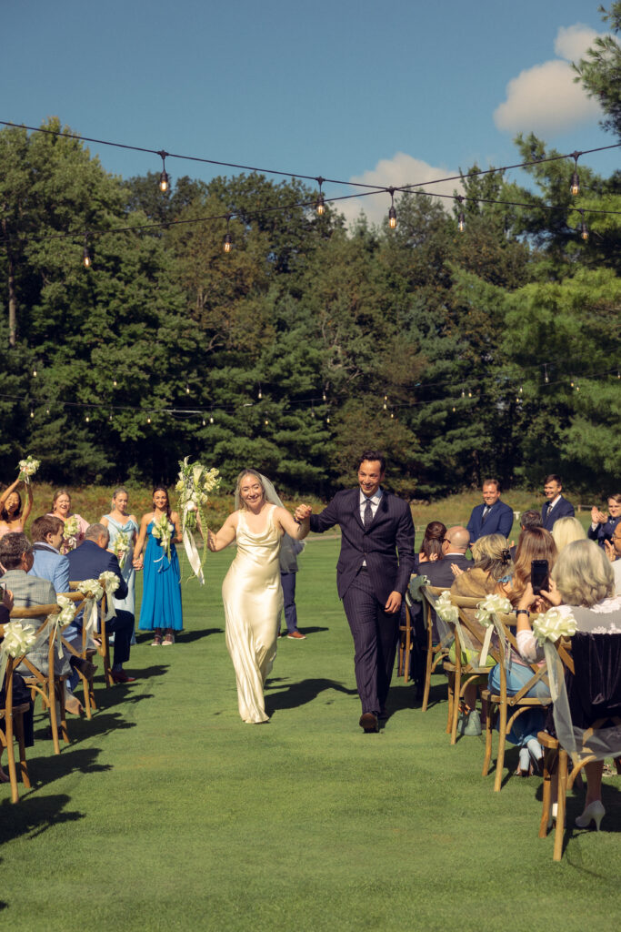 a bride and groom dance down the aisle together at their ceremony with documentary style wedding photos