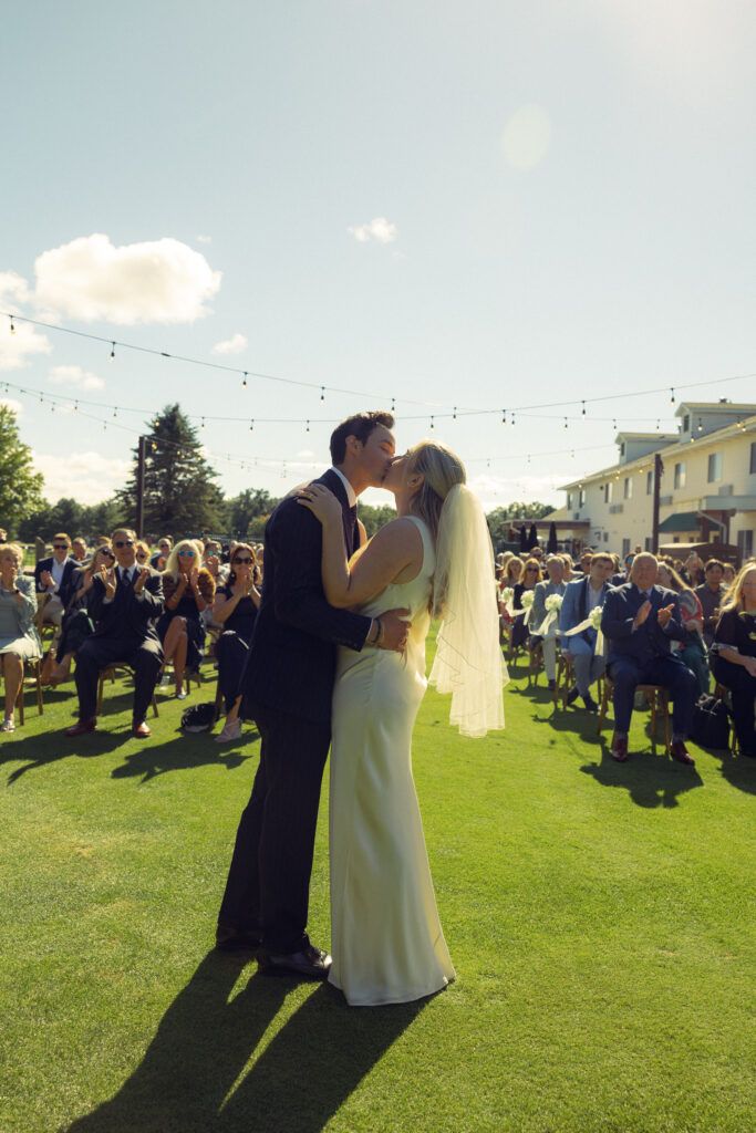 documentary style wedding photos, the bride and groom share their kiss in front of guests during their ceremony