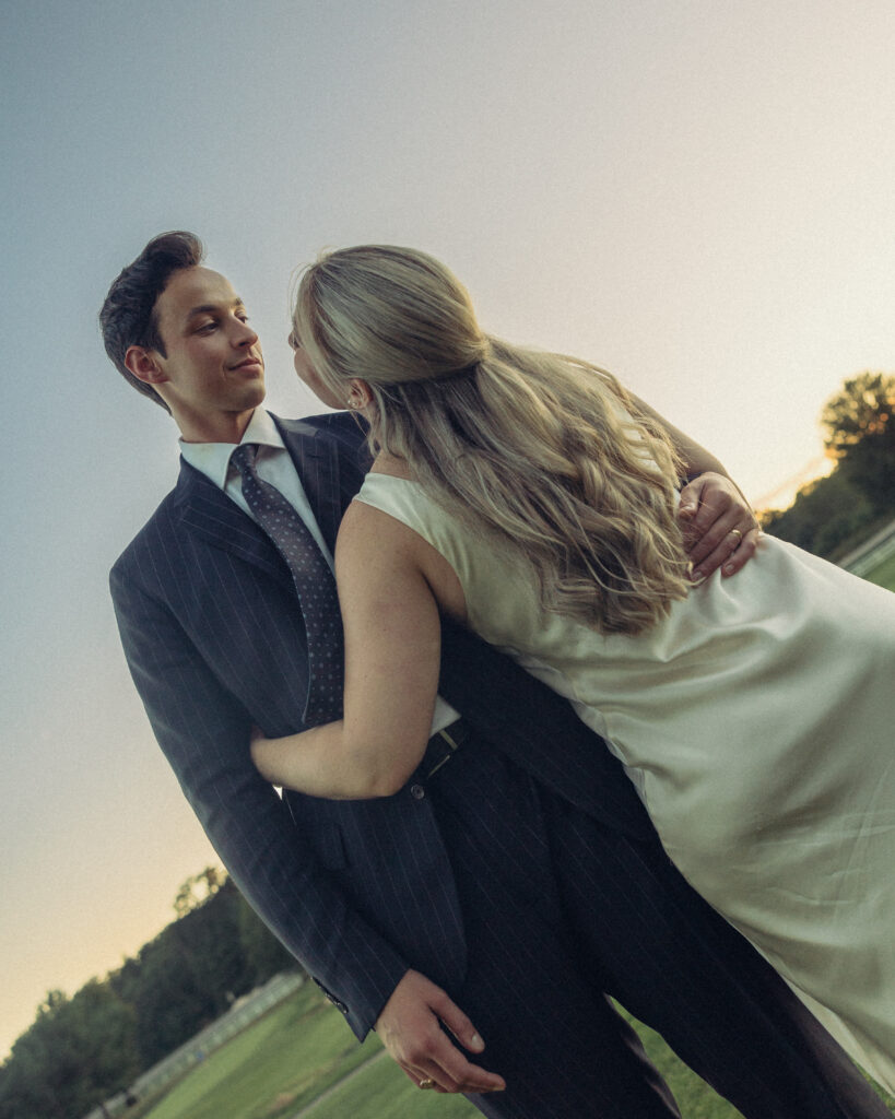 the bride and groom look each other in the eye as they share an embrace as the sun sets with their documentary style wedding photographer