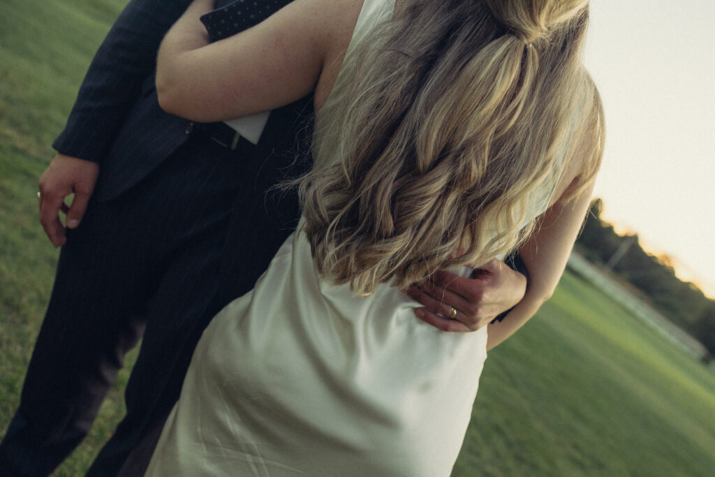 the groom rests his hand on his wife's waist during their documentary style wedding photos