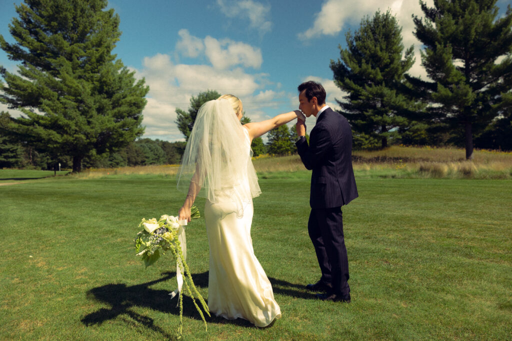 the bride holds her hand out for her husband to press a kiss to in documentary style wedding photos