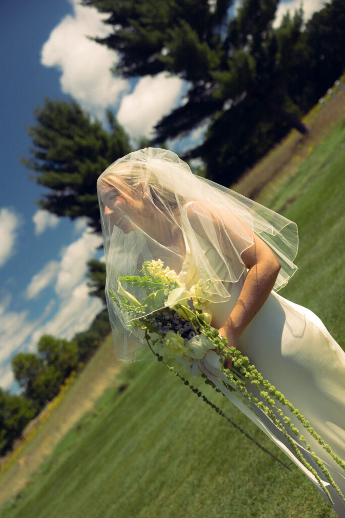 the bride smiles from under her veil while looking toward the sky