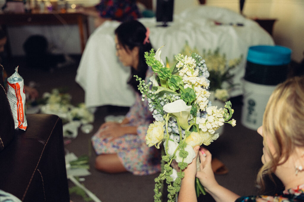 a bridesmaid puts together a bouquet of flowers on the hotel room floor during these documentary style wedding photos